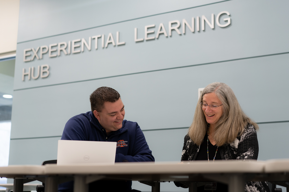 Two individuals sit at a table in the Experiential Learning Hub