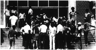 A black and white image of a crowd of people on the entrance staircase of a building