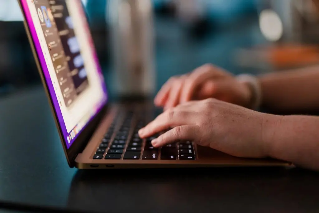Hands typing on a laptop keyboard
