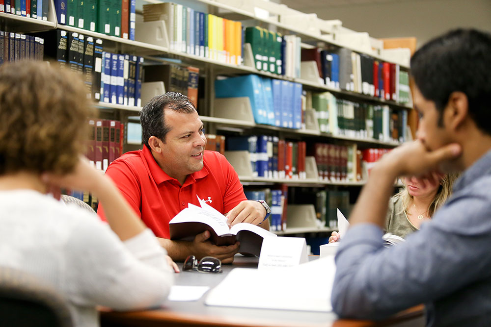 Four people sit around a table reading books at the library