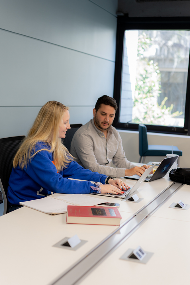 Two students work on laptops while studying in the Experiential Learning Hub