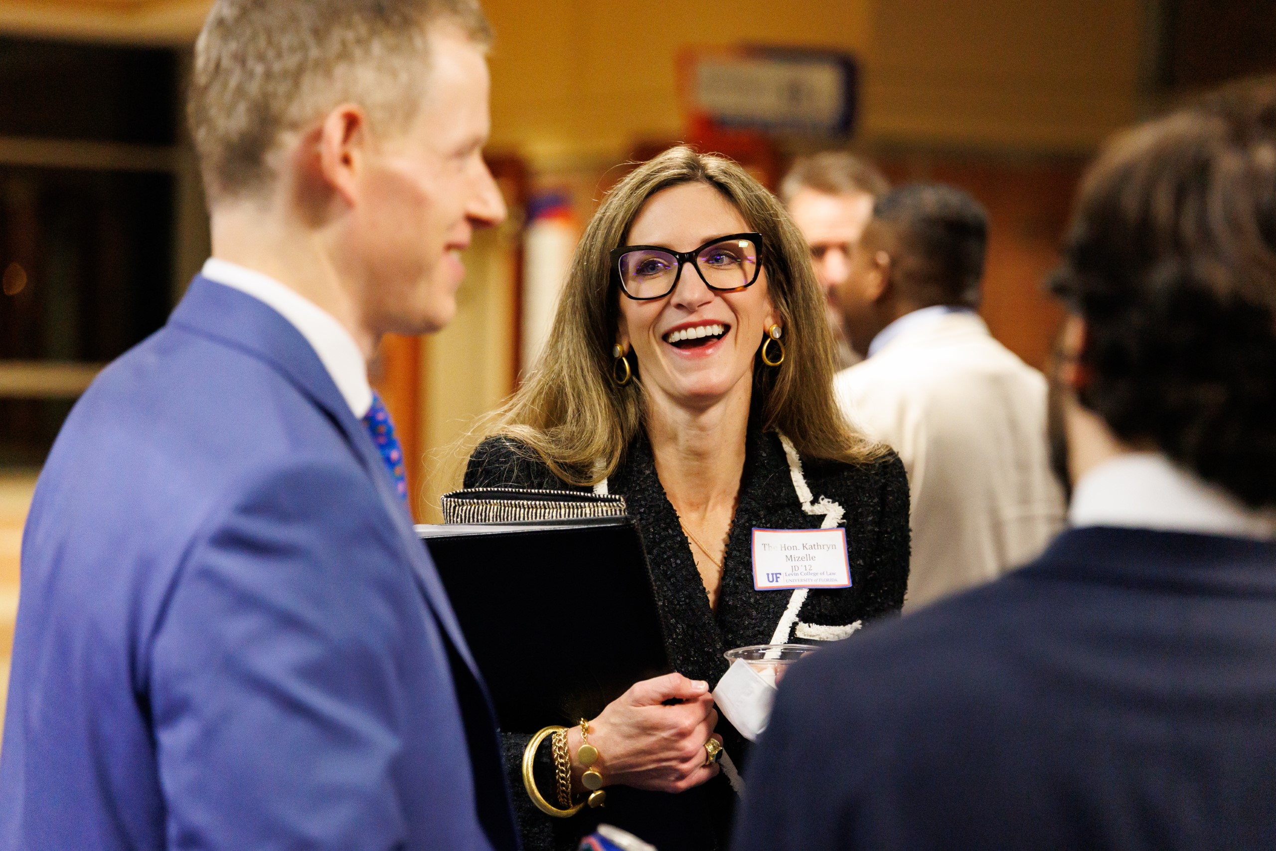 Judge Kathryn Kimball Mizelle (JD 12), District Judge, U.S. District Court for the Middle District of Florida, smiles as she speaks to guest at the celebration reception for UF Law's Professor Dennis Calfee and his 50 years of service to the law school. The celebration was held on Friday, November 15 at the University of Florida's Champions Club at Ben Hill Griffin Stadium. The reception included a welcome from Dean Merritt McAlister, and remarks from Masters of Ceremony Judge Robert Luck (JD 04), U.S. Circuit Judge, U.S. Court of Appeals for the 11th Circuit, and Judge Kathryn Kimball Mizelle (JD 12), District Judge, U.S. District Court for the Middle District of Florida. Additional guest speakers reflected on Professor Calfee's 50 year career and the impact that he has had at UF Law and beyond. After recognitions and presentations, Judge Luck and Judge Mizelle made the closing remarks.